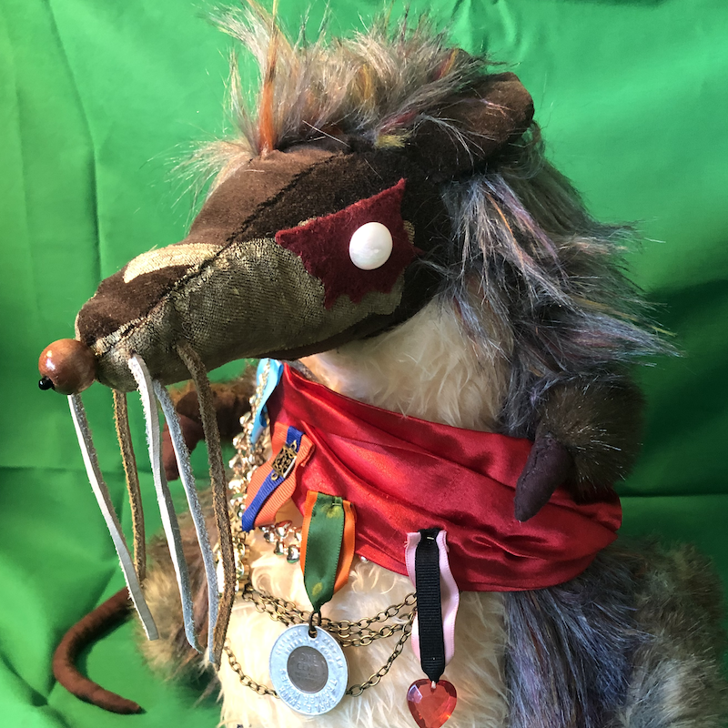 A rat plush with grey fur, a tan belly, and long whiskers, wearing a red silk sash decorated with military medals. Picture links to project page.